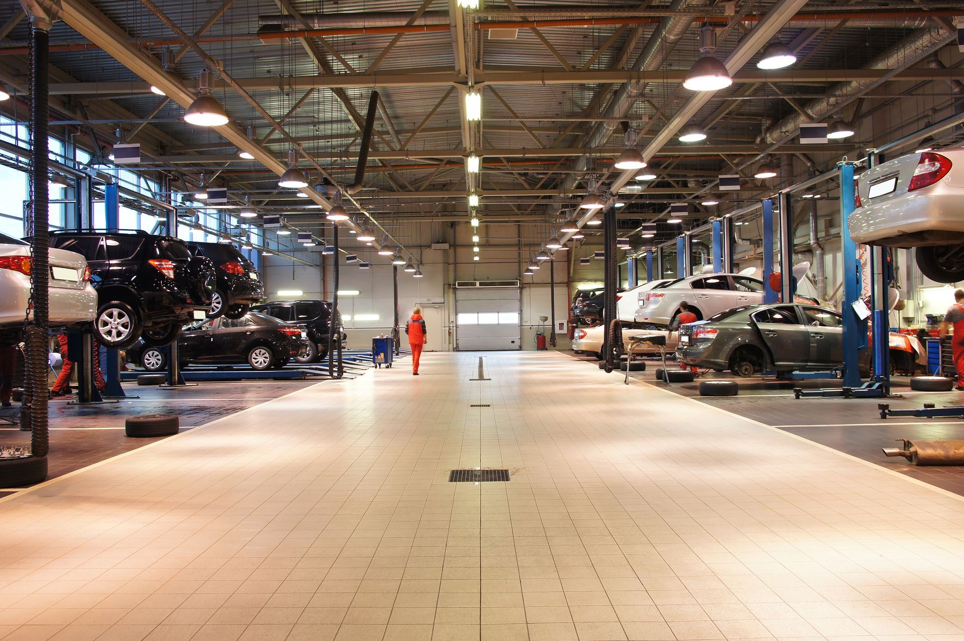 Car repair garage with cars on lifts and a worker standing in the central aisle