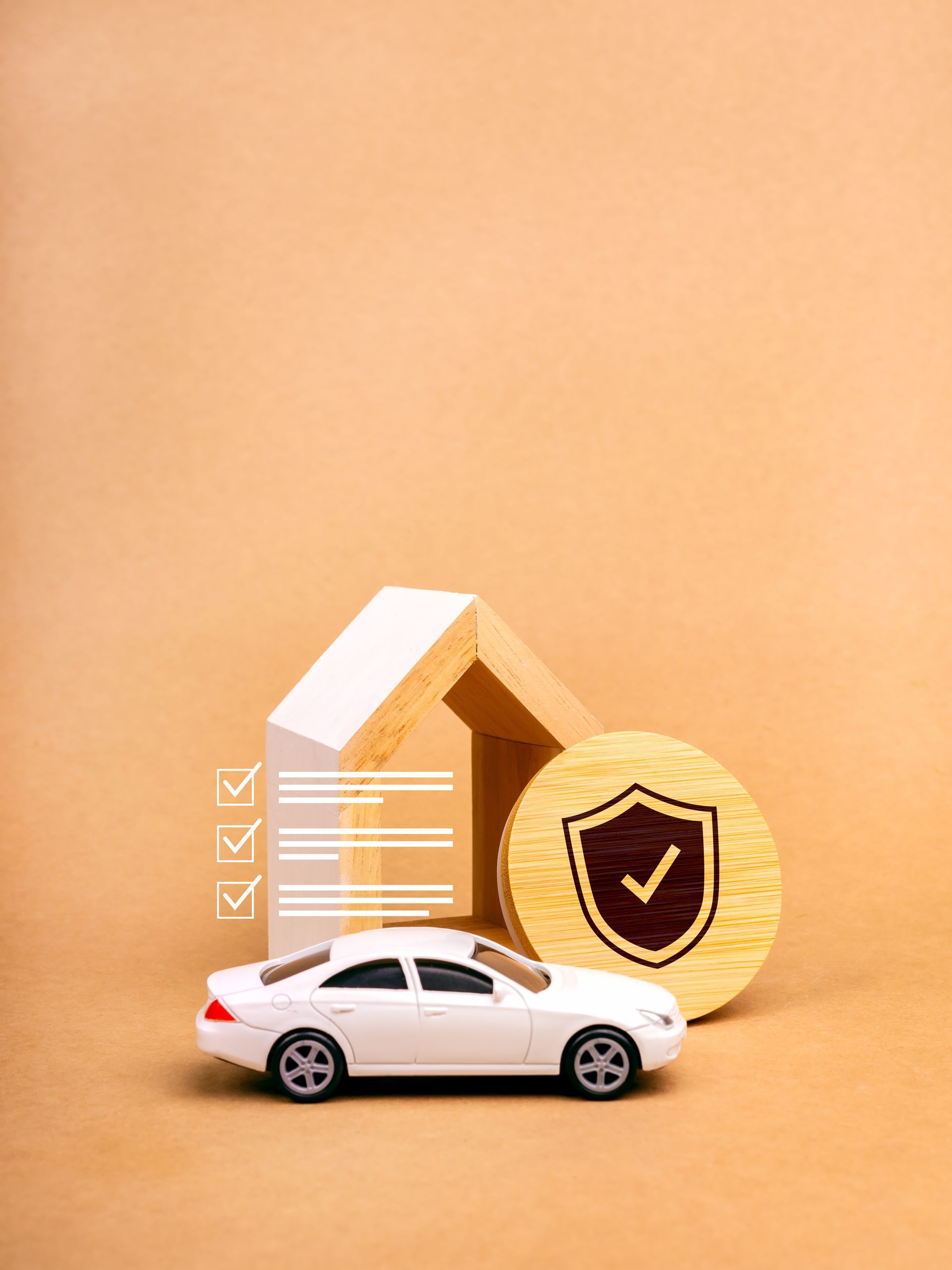 White car beside a house model and shield icon, suggesting home and auto insurance