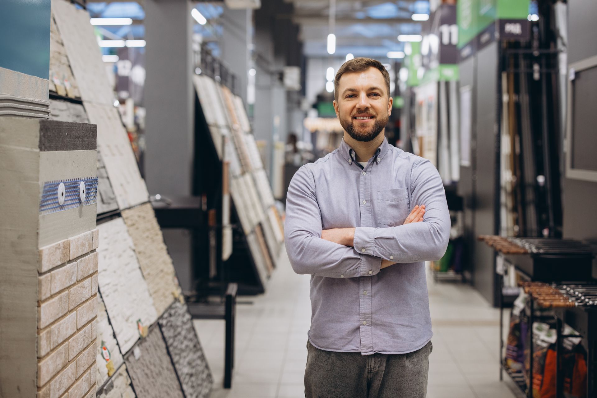 Smiling man standing with crossed arms in a building materials store.