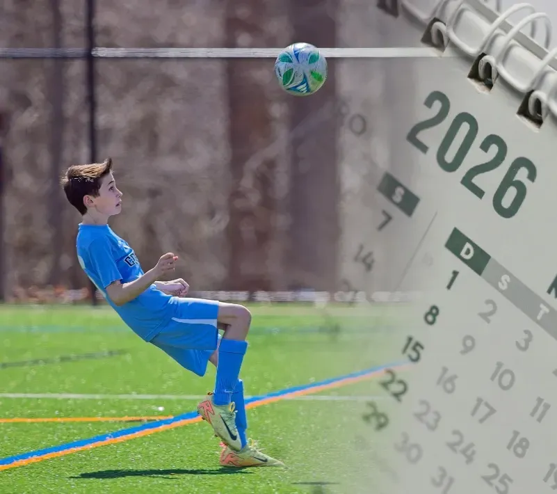 Boy in blue soccer uniform kicking a ball on a green field, with a 2026 calendar overlay.