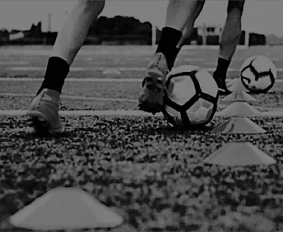a black and white photo of two people playing soccer on a field .
