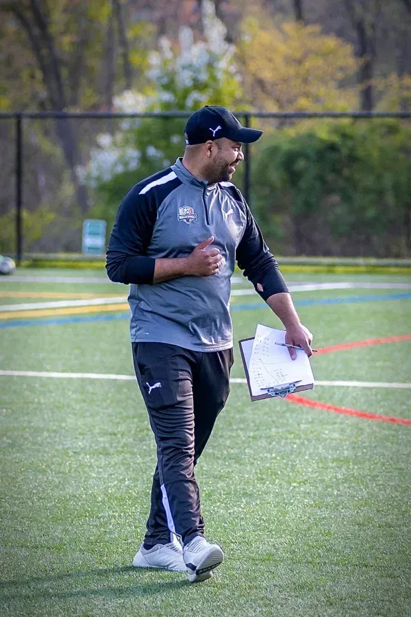 Coach evaluating players during tryouts. Coppermine Soccer Club's coach walking on the field evaluating youth club soccer players during a tryout session.