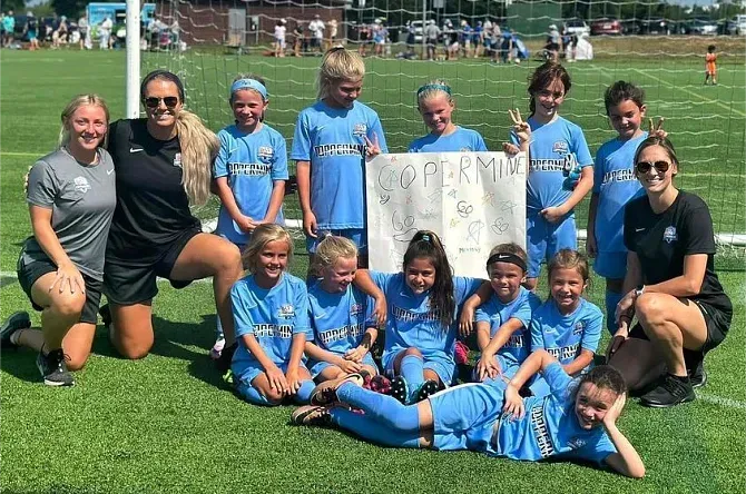 a group of young girls are posing for a picture on a soccer field .