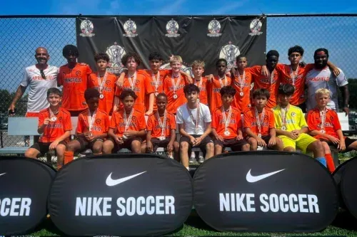 Soccer team posing on a field in orange uniforms behind Nike Soccer banners