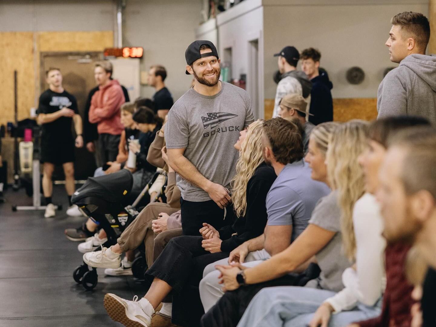 A group of people are sitting in a gym talking to each other.