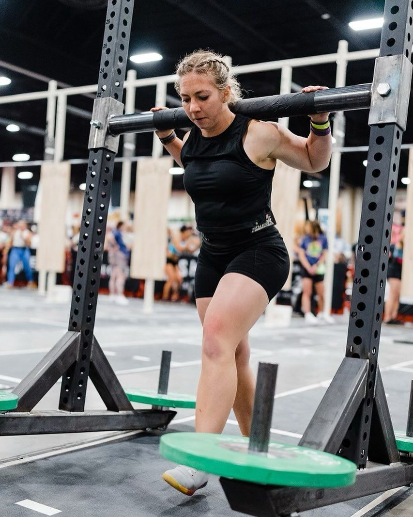A woman is lifting a barbell in a gym.