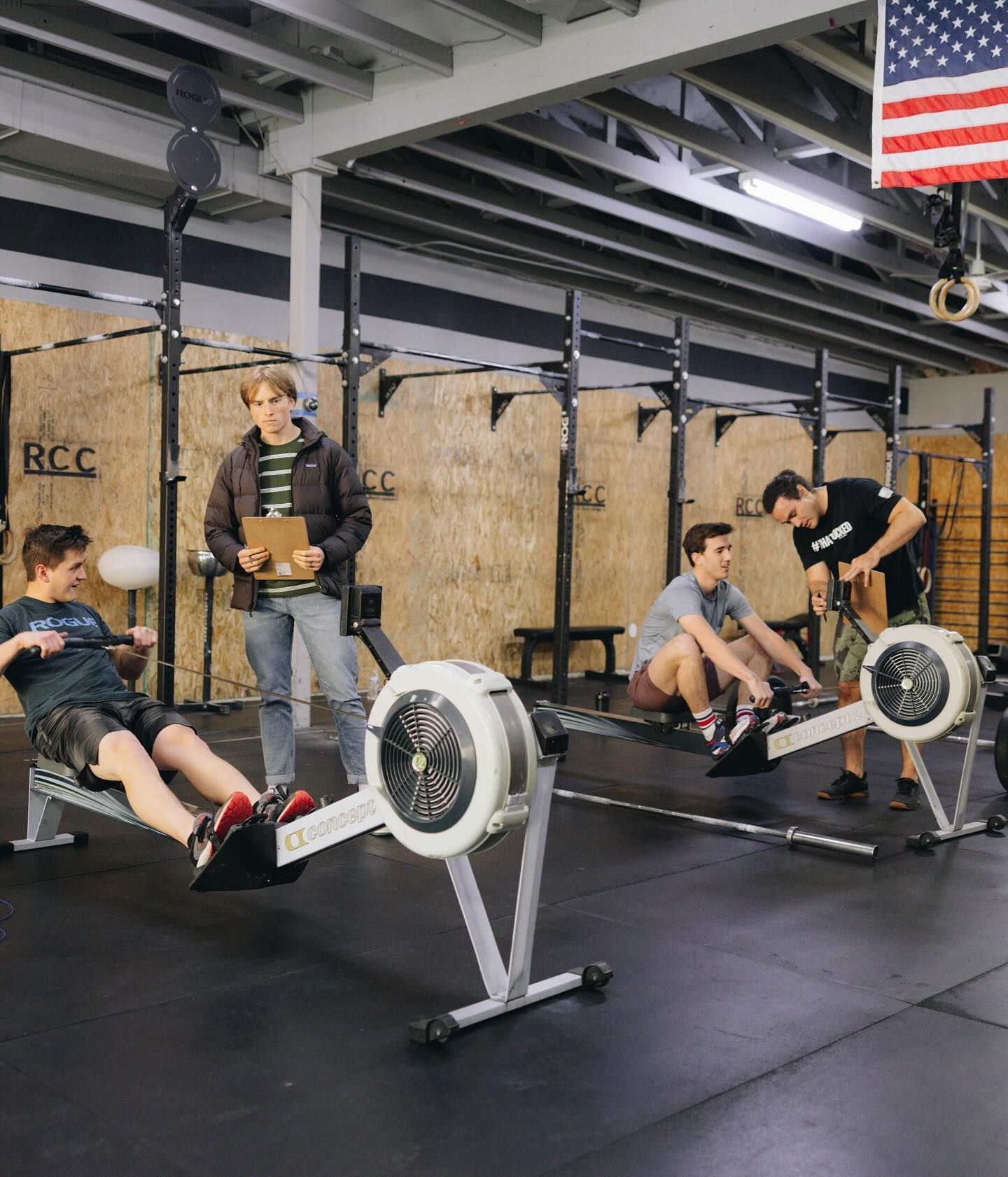 A group of men are using rowing machines in a gym.