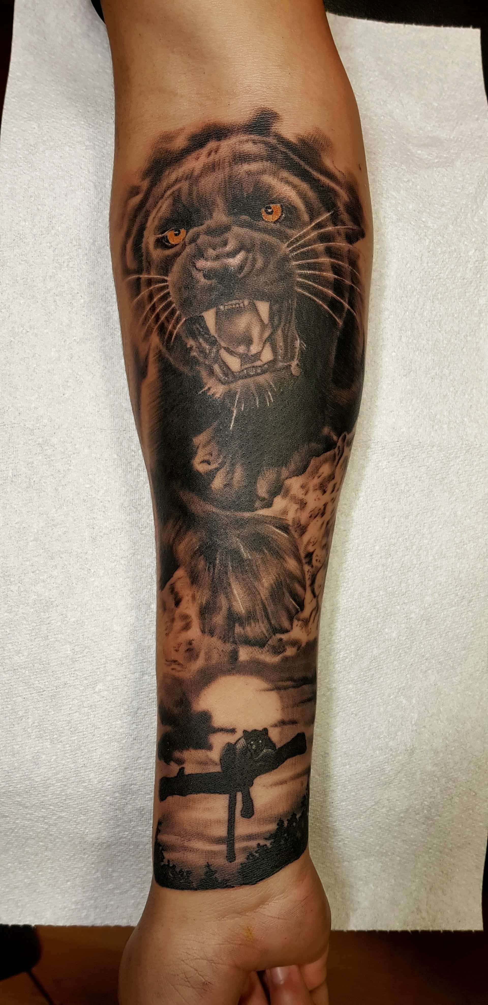 Black and grey forearm tattoo featuring a roaring panther head above a silhouette of a person on a swing at sunset.