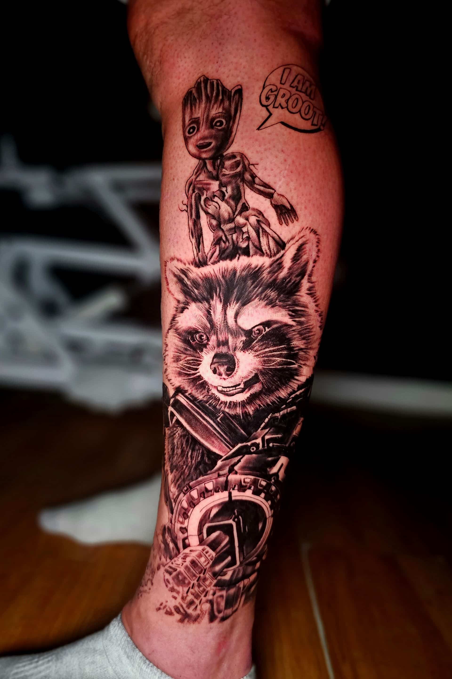 A black-and-grey tattoo on a person's leg featuring Rocket Raccoon and Baby Groot with a speech bubble saying 