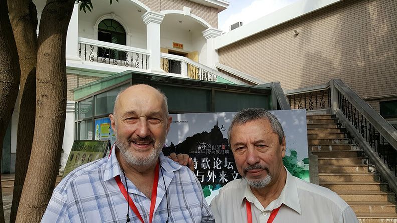 Two men are posing for a picture in front of a building.