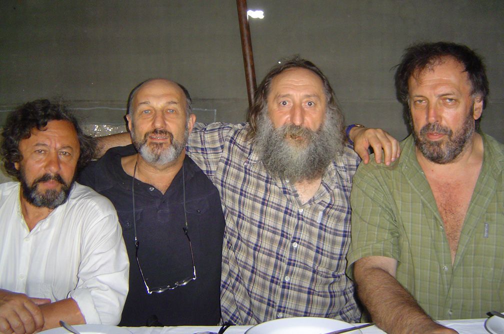 Four men with beards are posing for a picture
