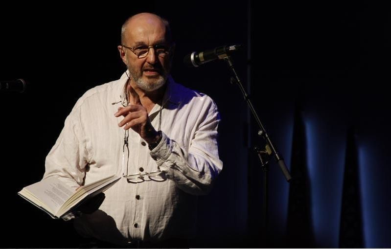 A man is standing in front of a microphone holding a book.