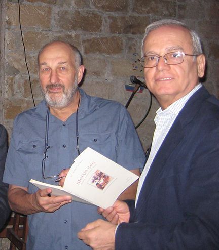 Two men are standing next to each other and one is holding a book that says ' mediterranean ' on it