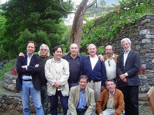 A group of men posing for a picture in front of a stone wall