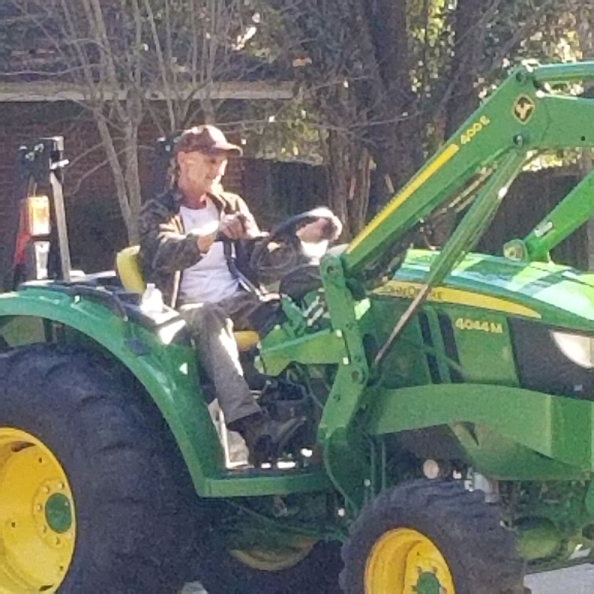 Person driving a John Deere tractor. Green and yellow tractor, outdoors.