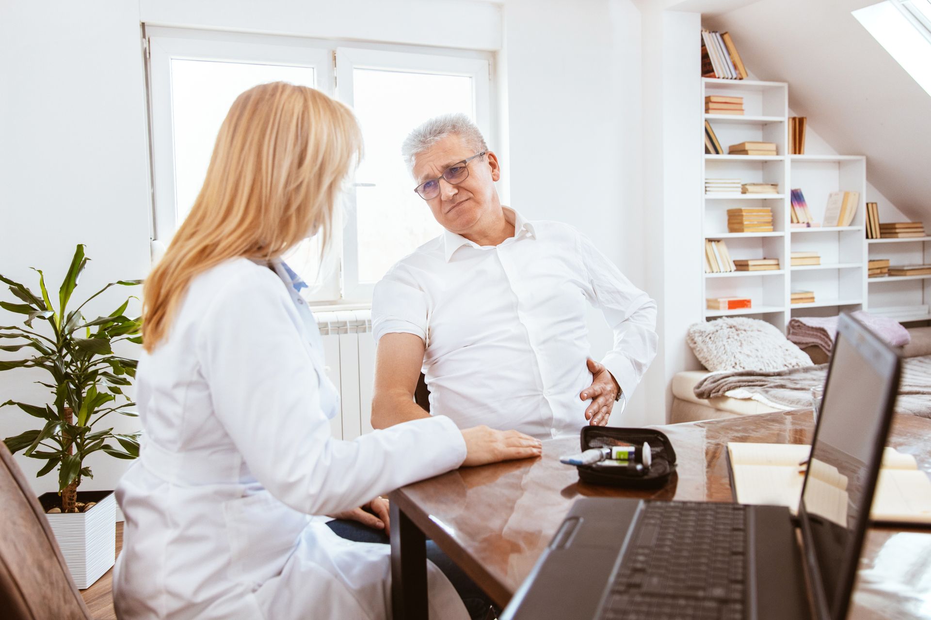 A Doctor and a Patient are Sitting at a Table with a Laptop — Orlando, FL — Central Florida Kidney Specialists A Doctor and a Patient are Sitting at a Table with a Laptop — Orlando, FL — Central Florida Kidney Specialists