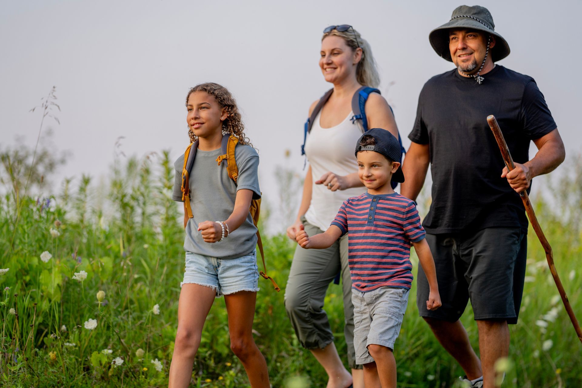 A family is walking through a grassy field holding hands.