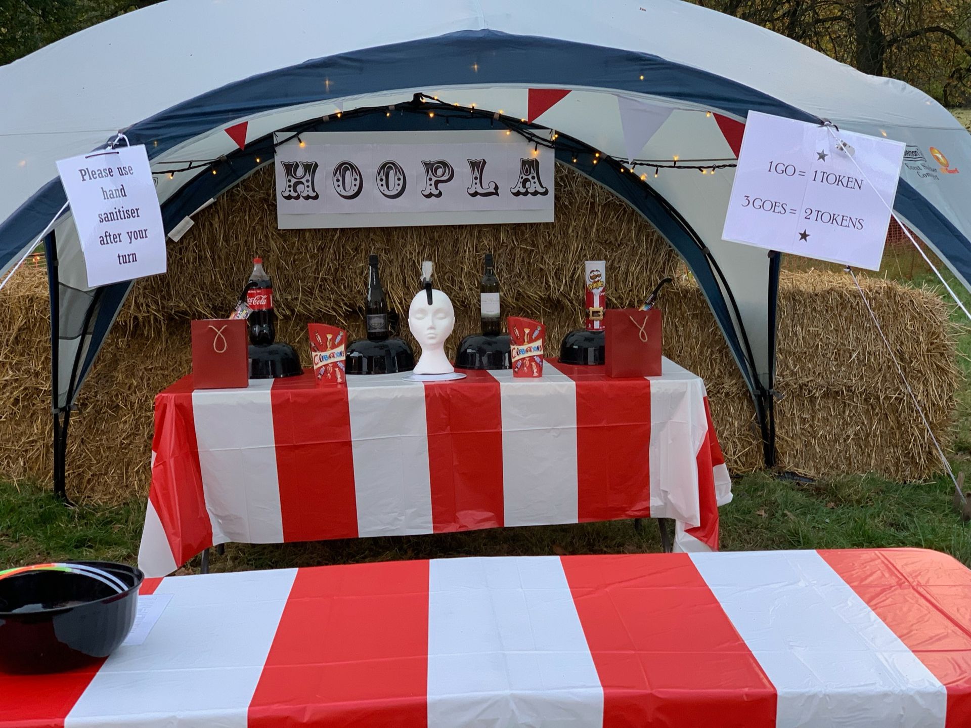 A carnival game booth with red-and-white striped tablecloths. Sign reads 