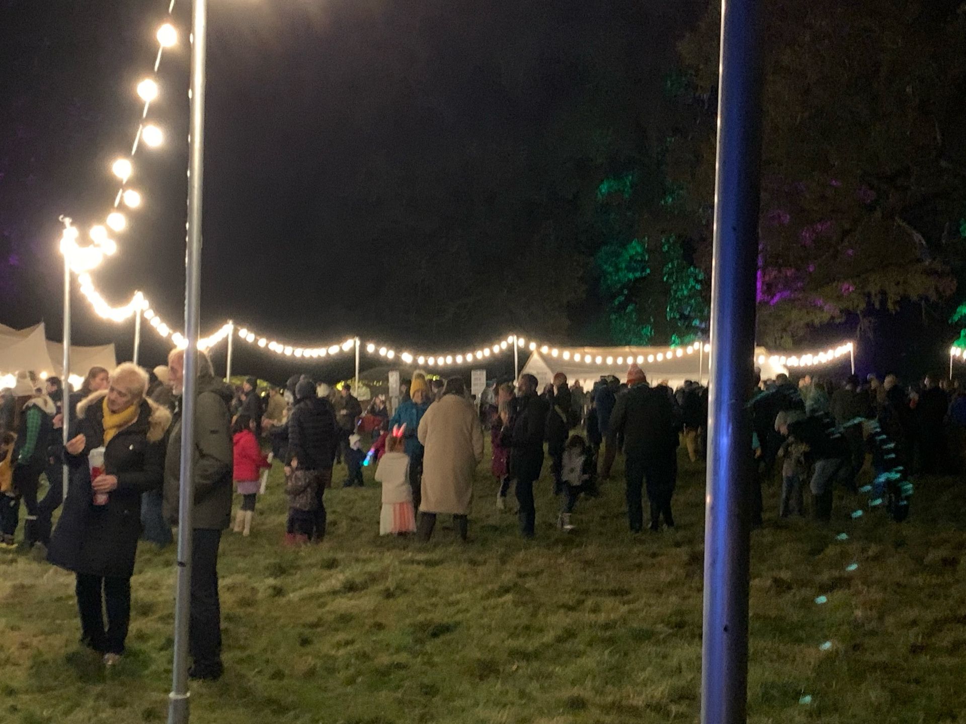 People gather outdoors at night under string lights.