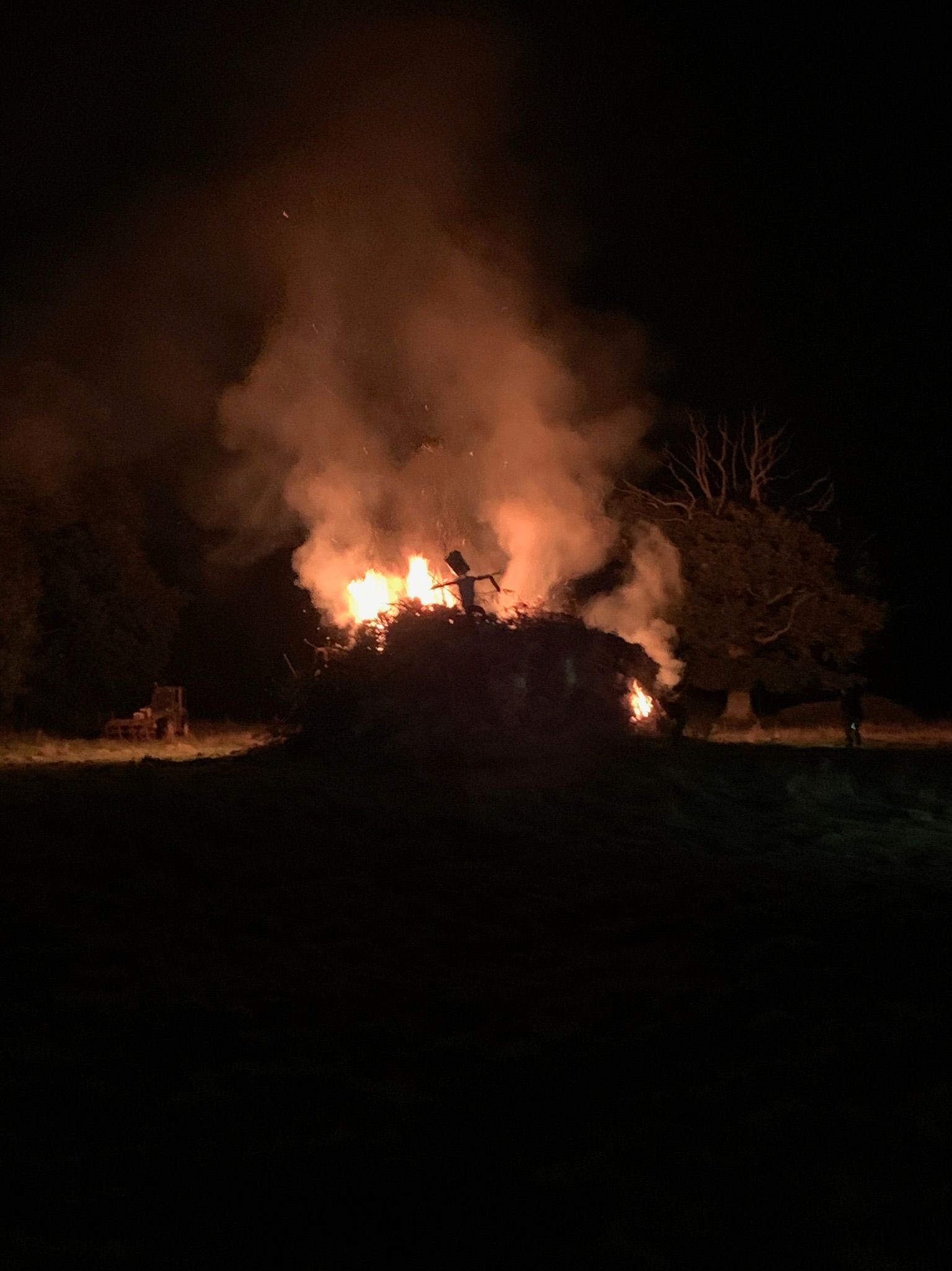 Fire burning brightly at night, orange flames and smoke.