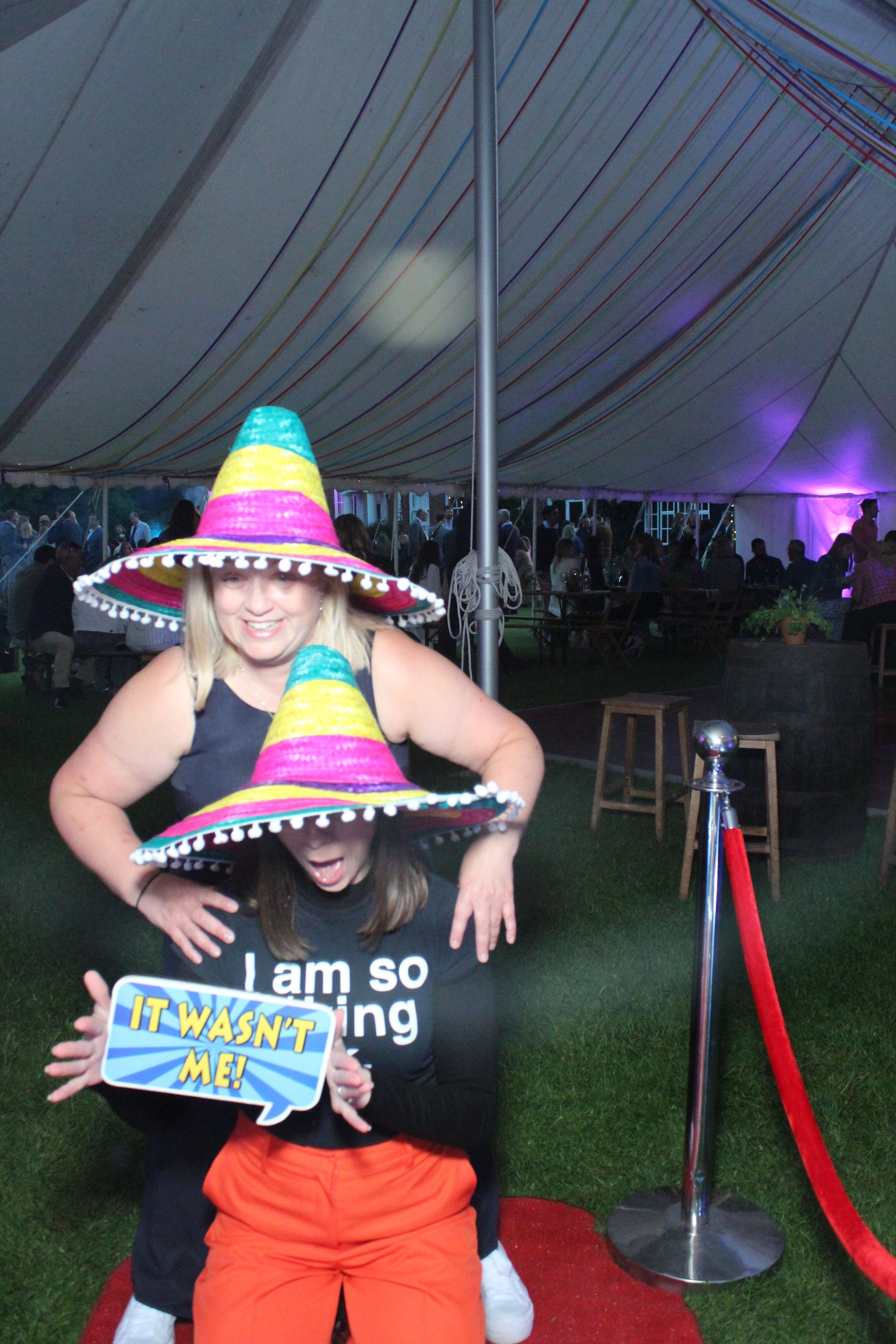 Two people in sombreros, smiling, holding a prop that says 