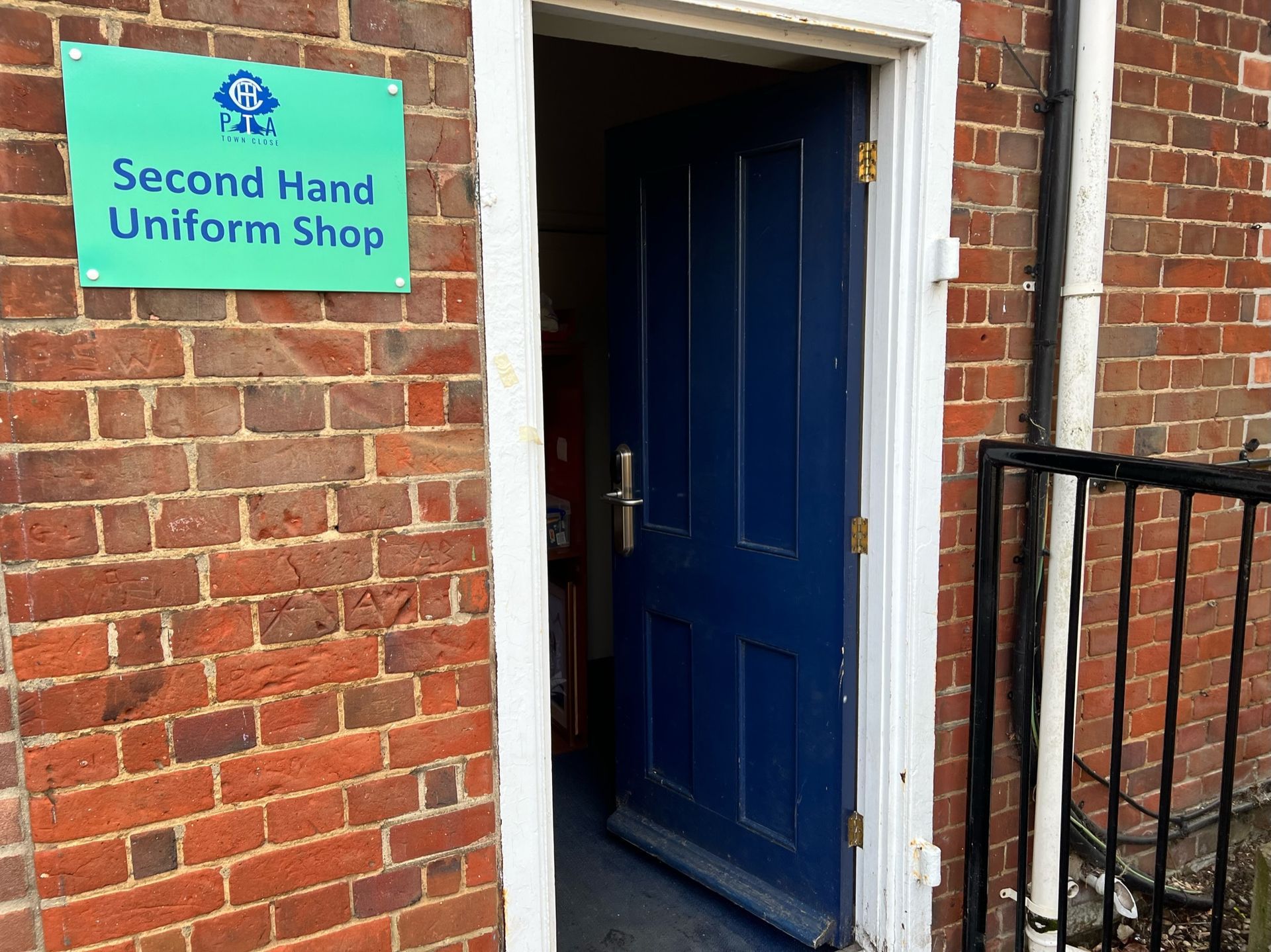 A brick building with an open blue door and a sign that reads