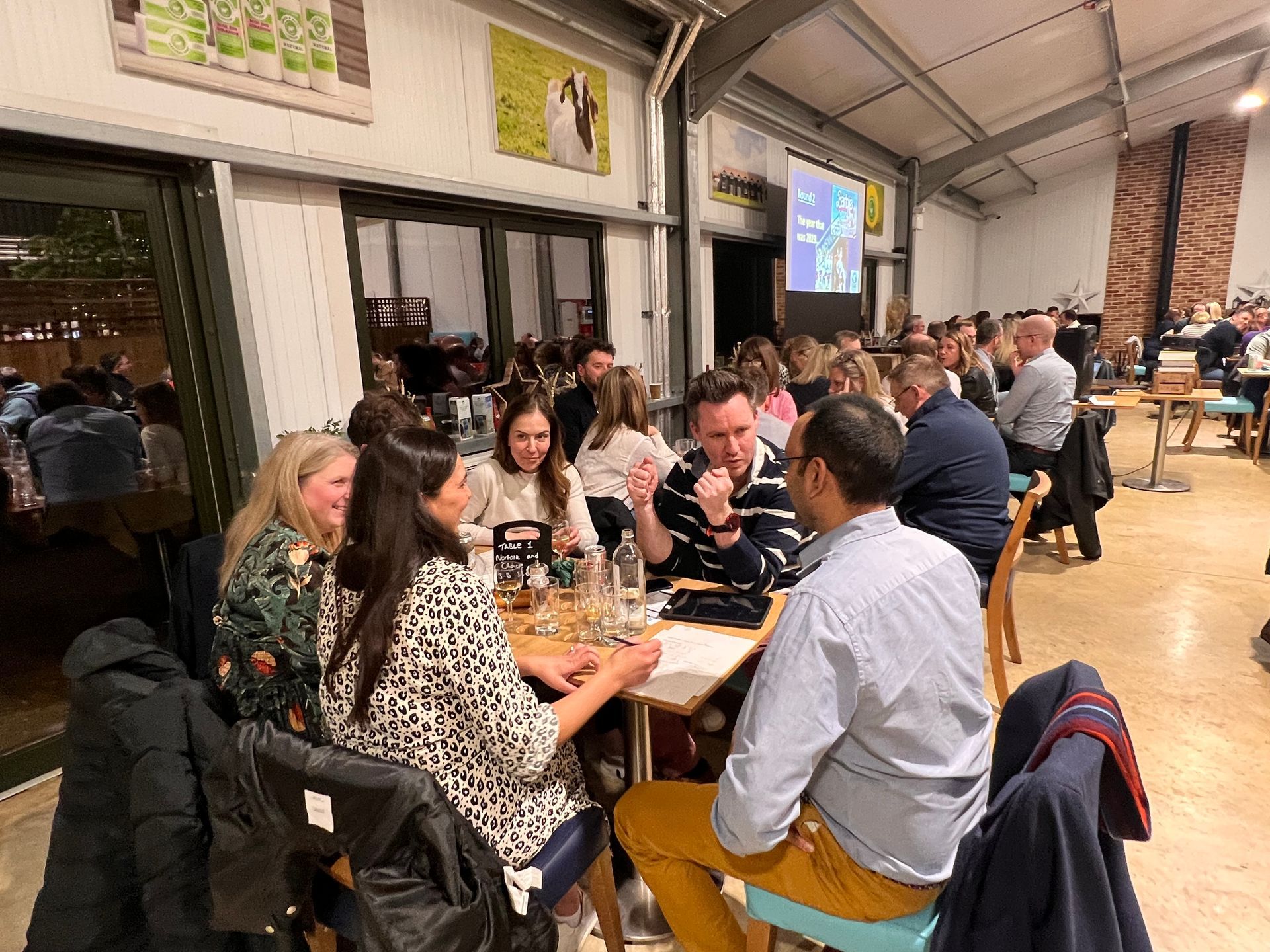 People seated at tables, socializing in a brightly lit indoor space.