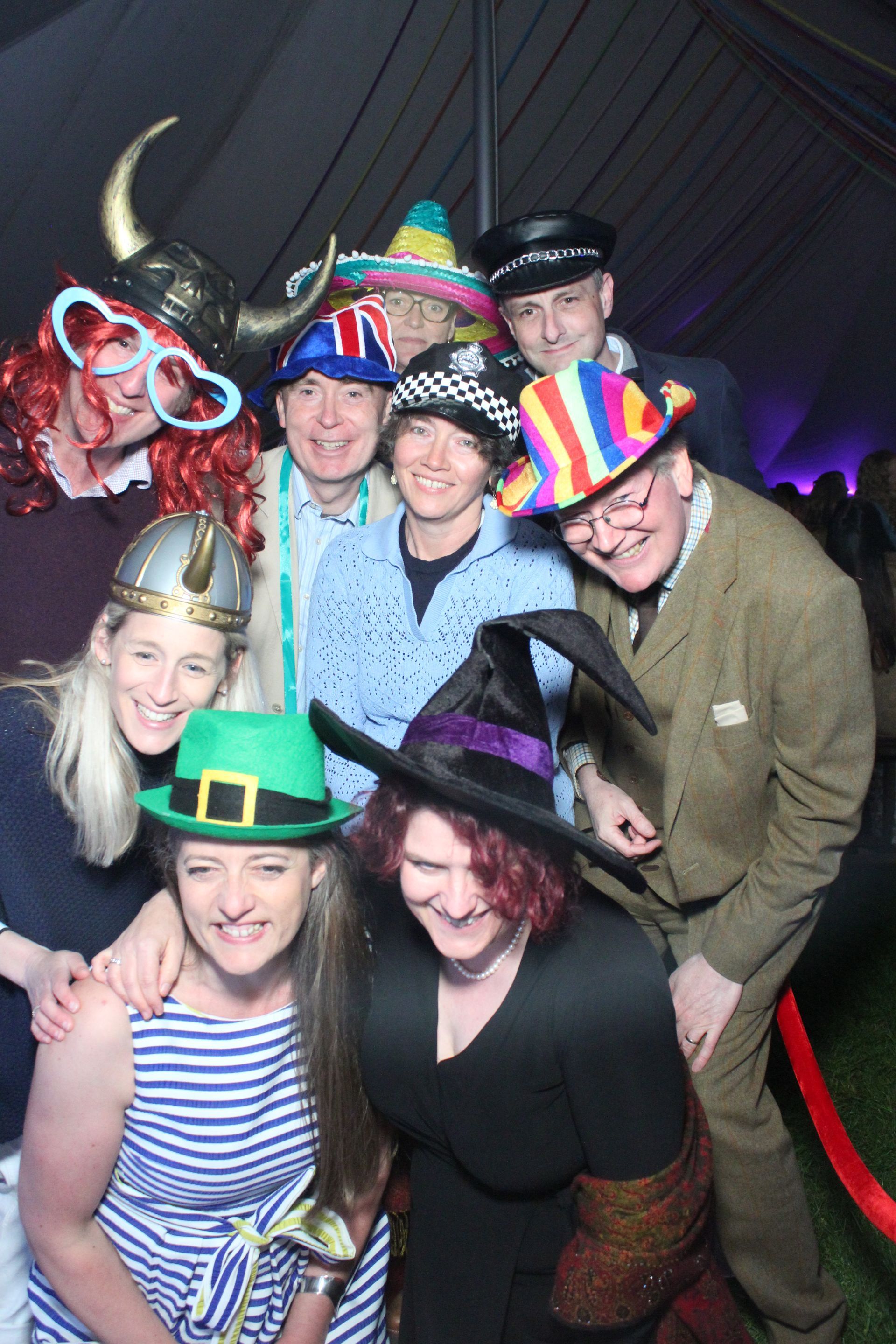 Group of people wearing silly hats posing for a photo at an event, some smiling.