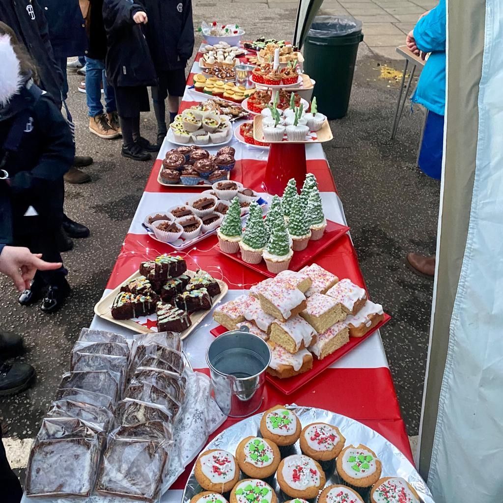 A table of baked goods, including brownies, cupcakes, and cookies, at an outdoor event.