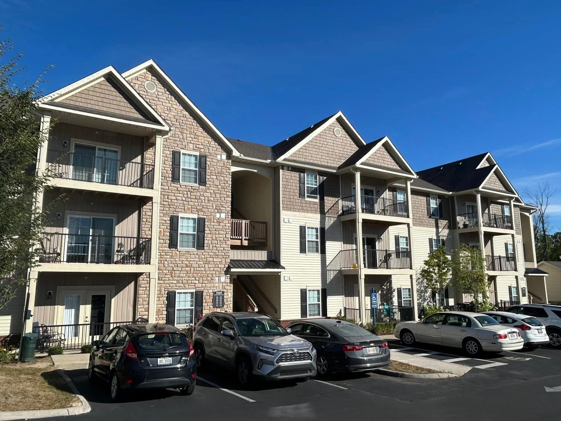 Apartment building exterior with parked cars under a clear blue sky