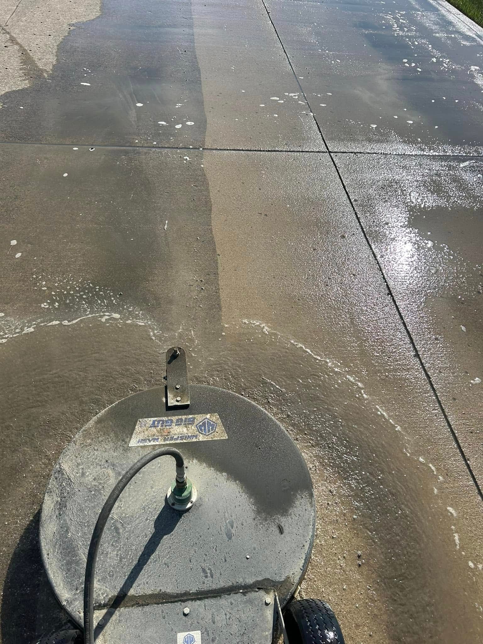 Concrete sidewalk with a circular utility cover and a spray-painted mark on wet pavement