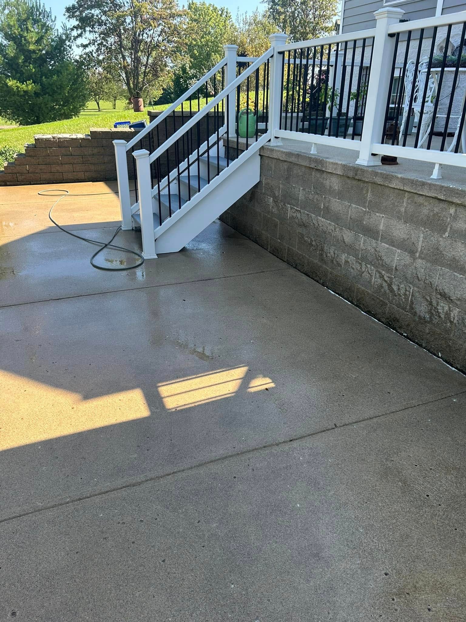 Concrete outdoor stairs with white railing beside a retaining wall on a sunny day