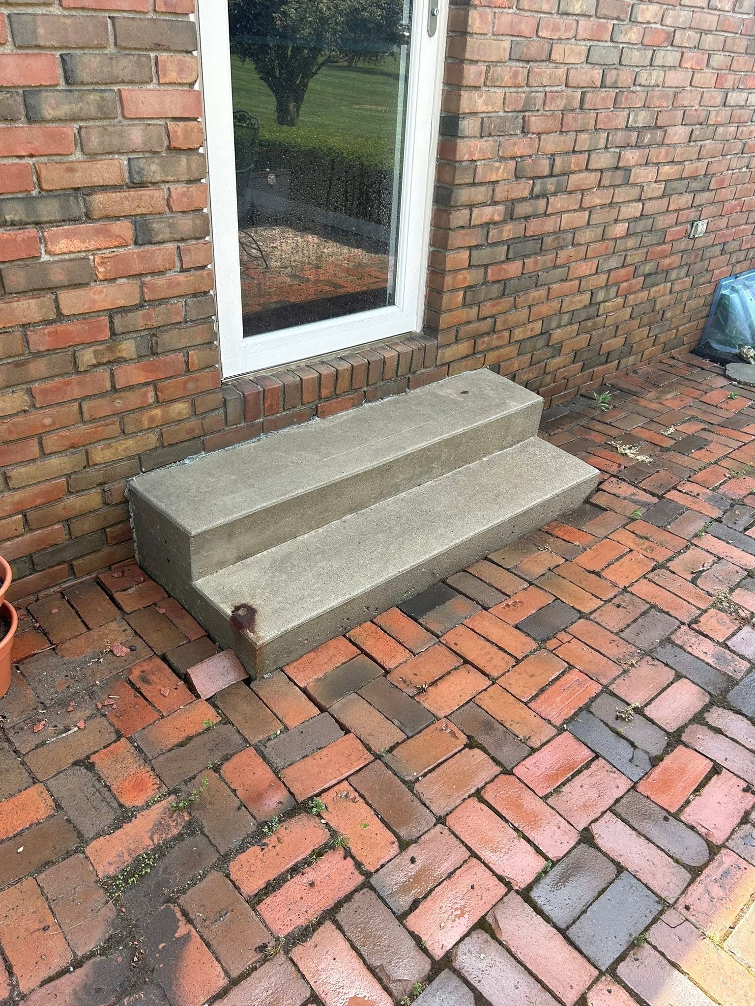 Brick patio steps leading to a back door beside a brick wall and brick walkway.