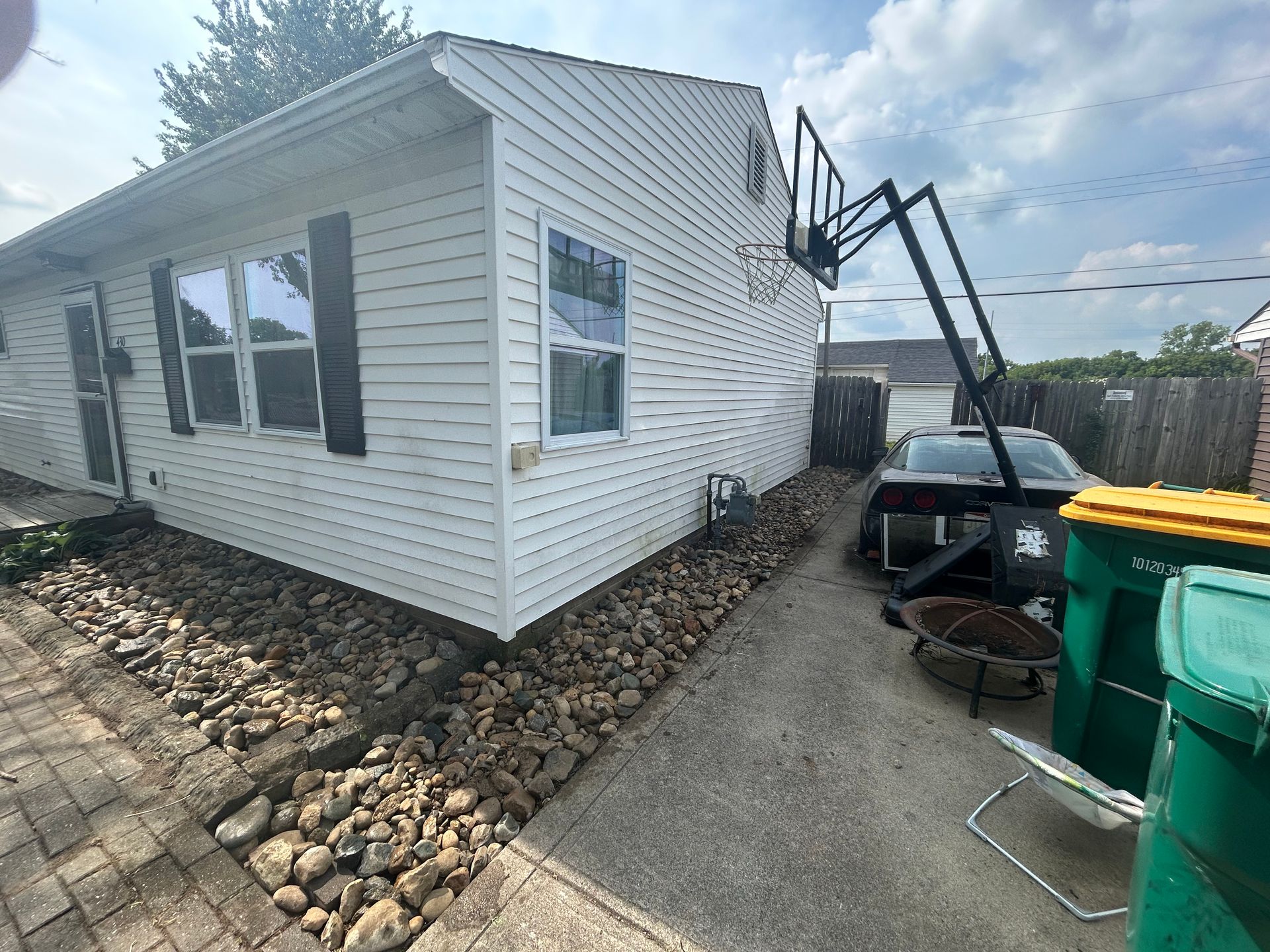 Exterior house siding with white utility supports and a small window on the side wall
