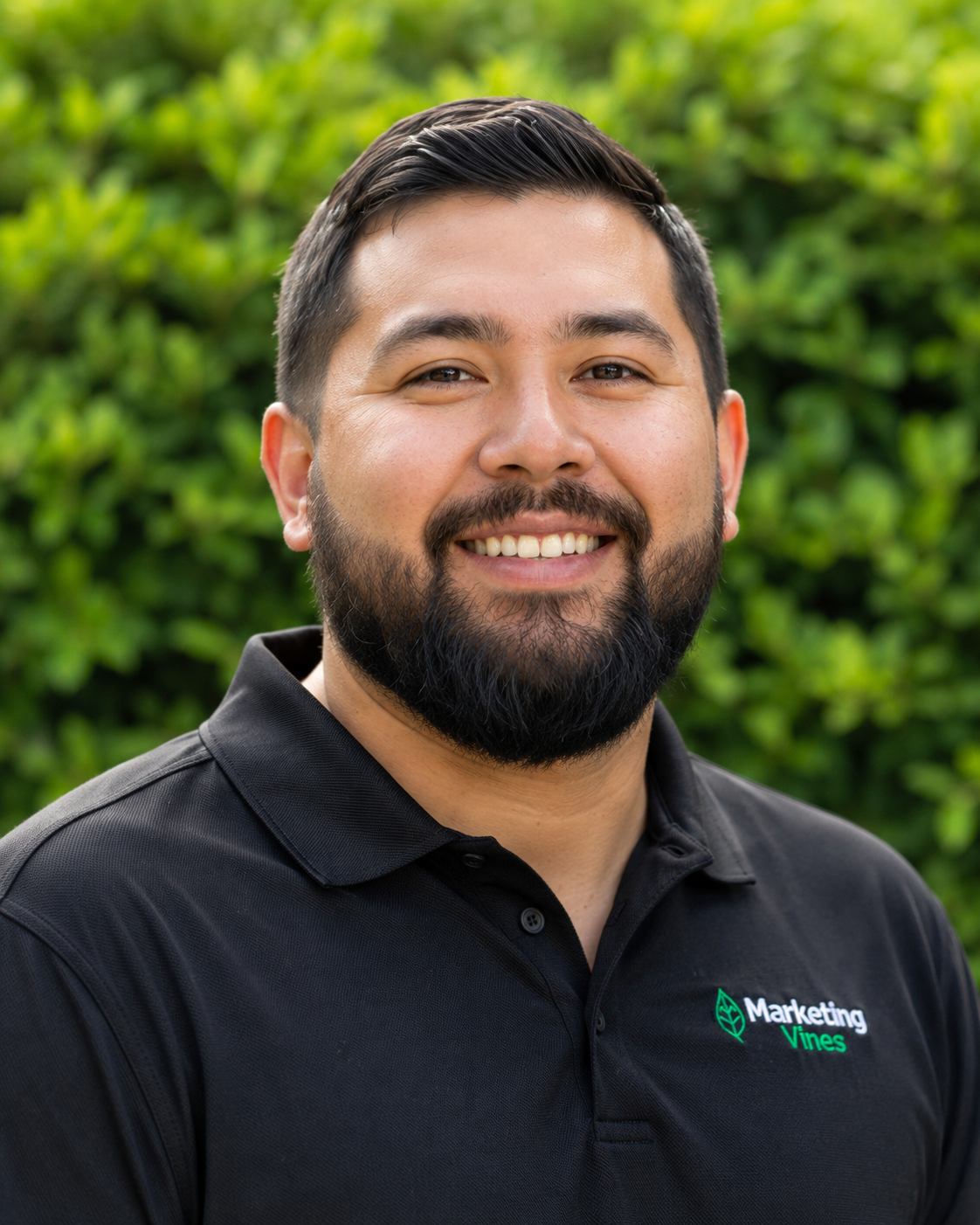 Ethan Calloway, SEO & Ai Visibility Specialist for Home Service Businesses Smiling person in a black polo shirt standing outdoors in front of green foliage