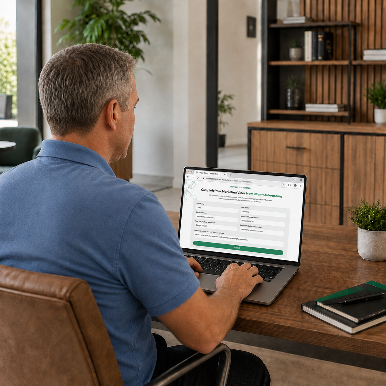 Person working on a laptop at a wooden table in a modern home office