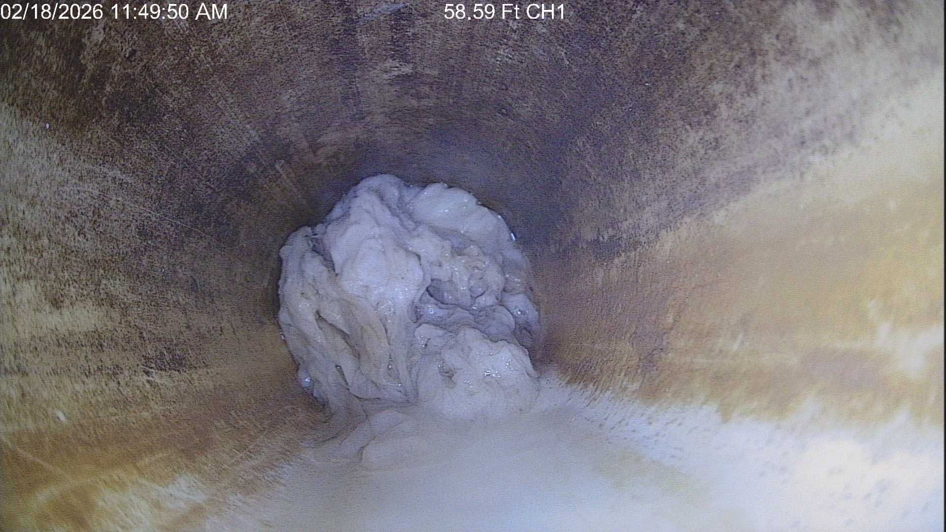 Large pale rock-like mass inside a dim, dusty tunnel or pipe, with rough brown-gray walls.