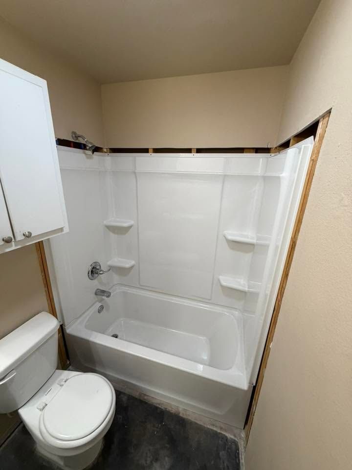 Small bathroom with a white toilet and bathtub shower surround.
