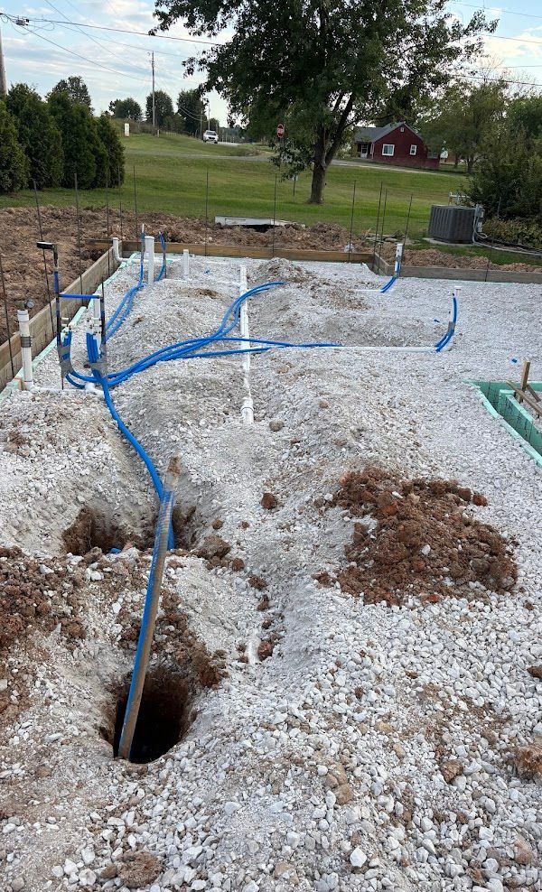 Construction site: concrete foundation walls, exposed plumbing pipes, and dirt.