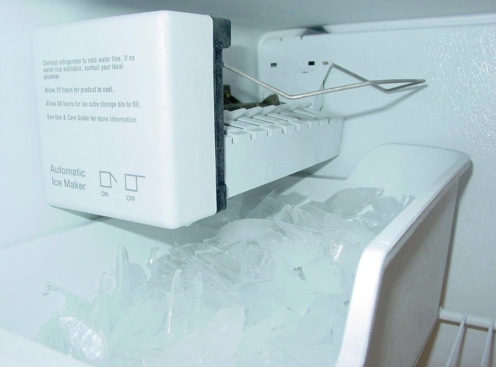 An ice maker in a refrigerator with ice in it