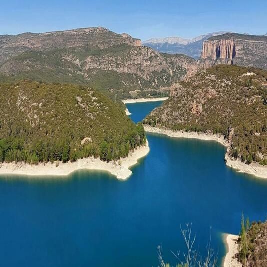 Una gran massa d'aigua envoltada de muntanyes i arbres.