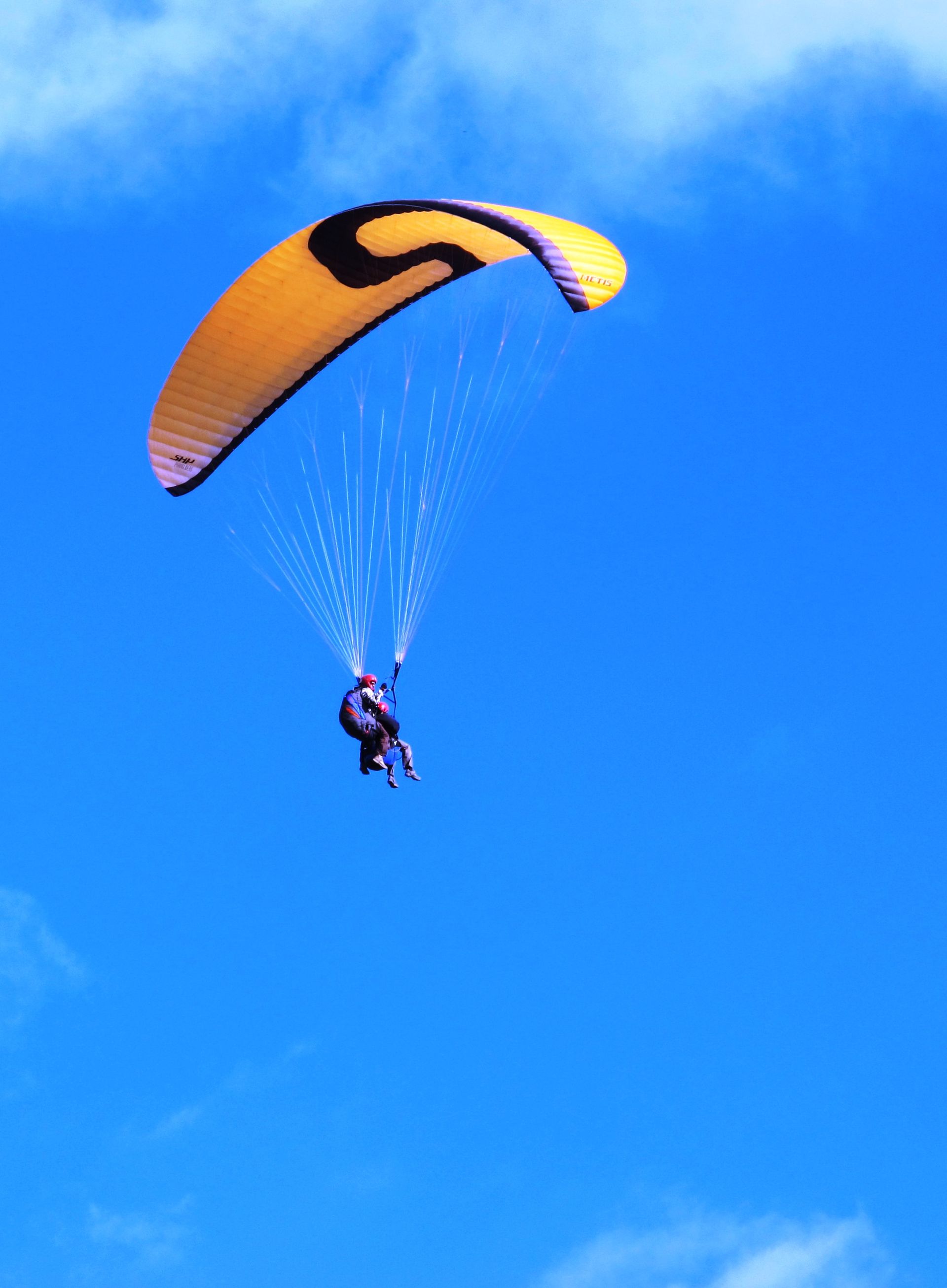 Una persona fa parasailing amb un paracaigudes groc amb la lletra s