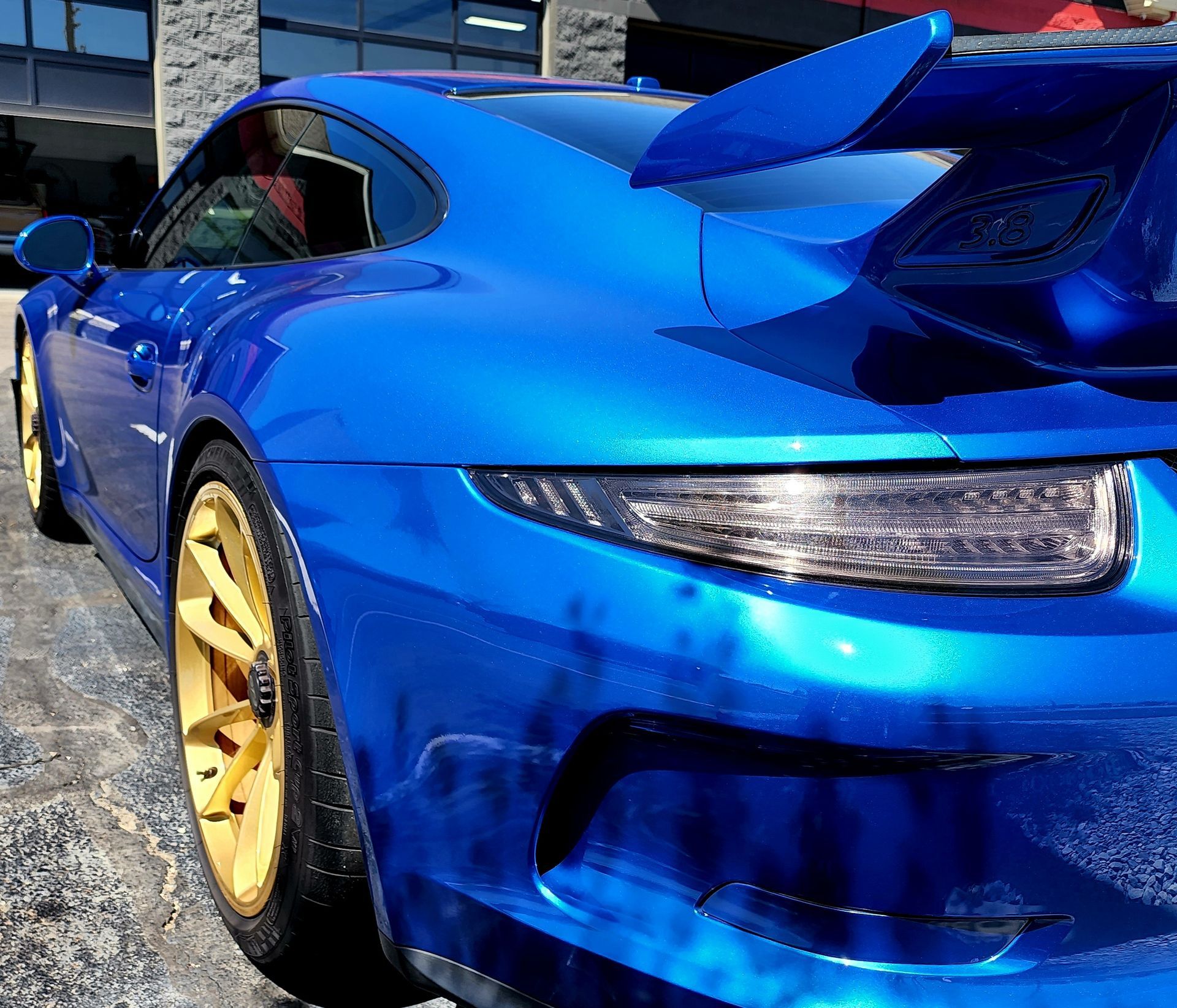 A blue sports car is parked in front of a building