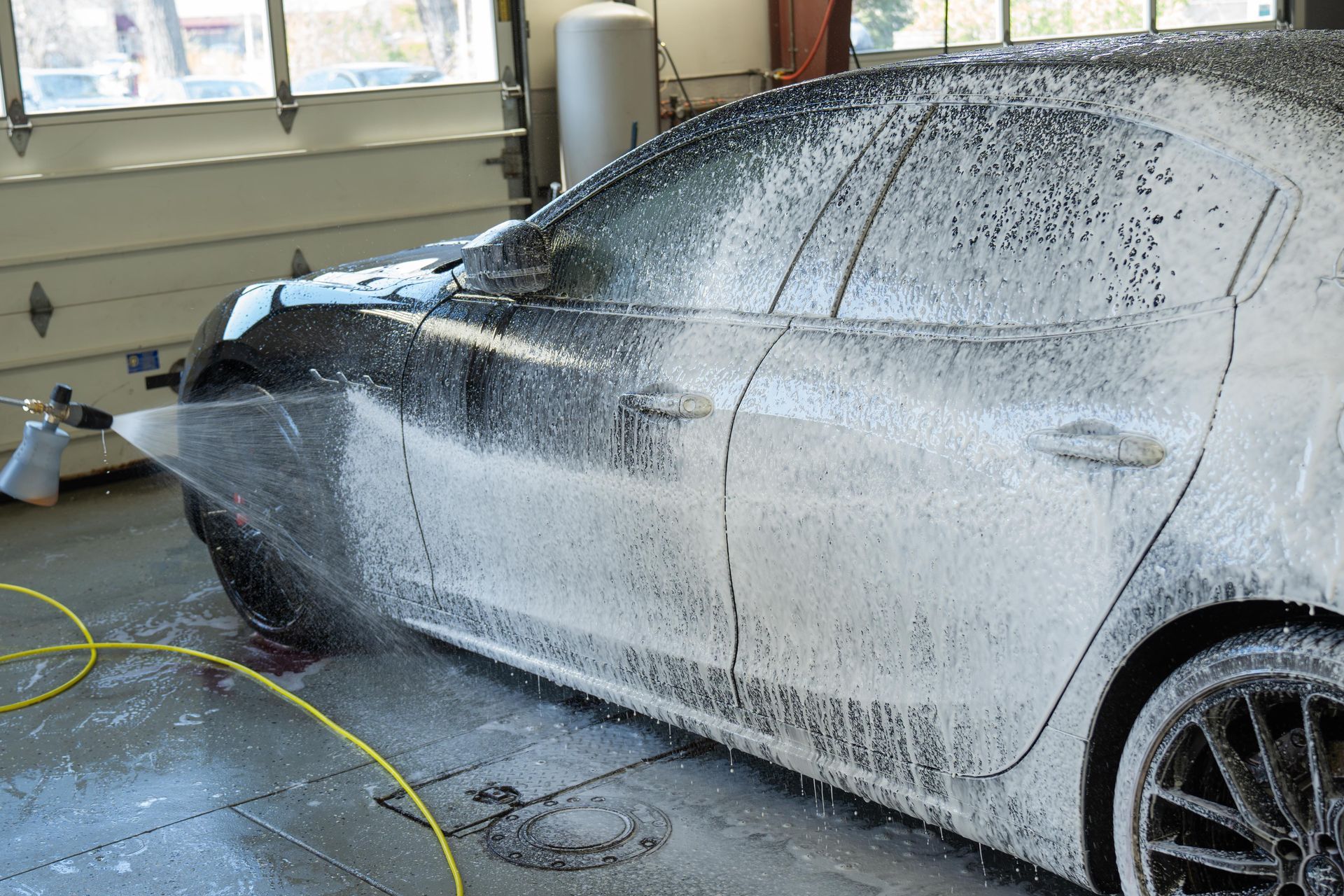 A car is covered in foam in a garage.