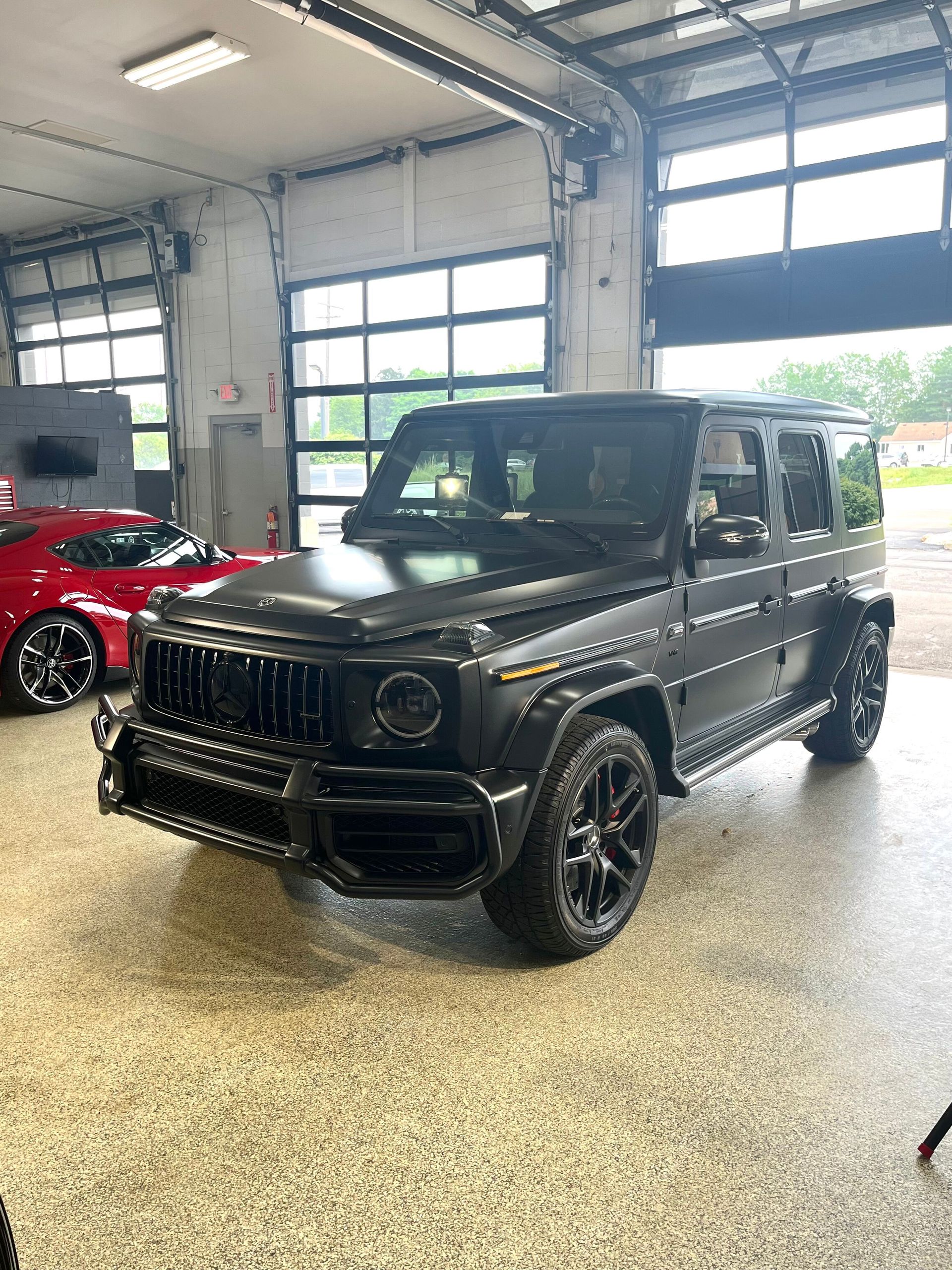 A black mercedes benz g63 amg is parked in a garage.