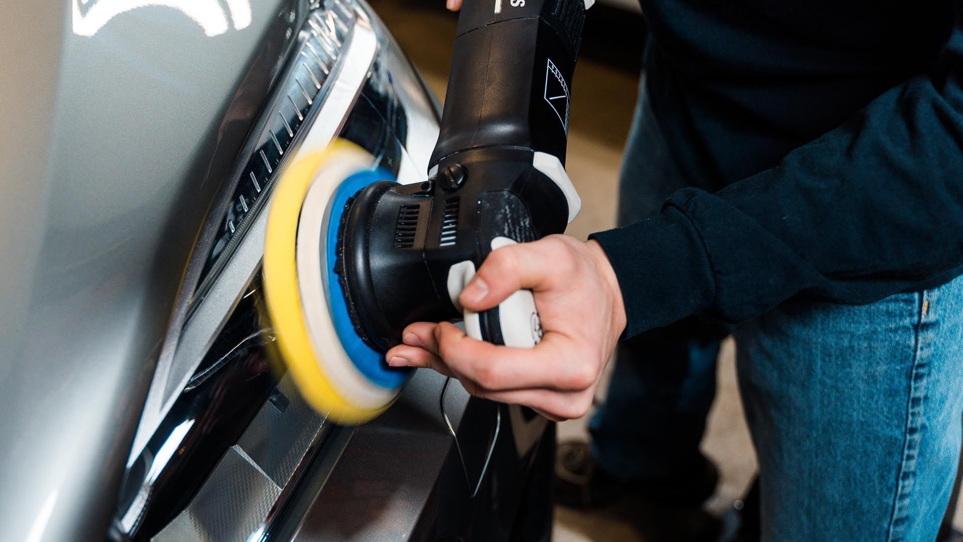 A man is polishing a car with a machine.