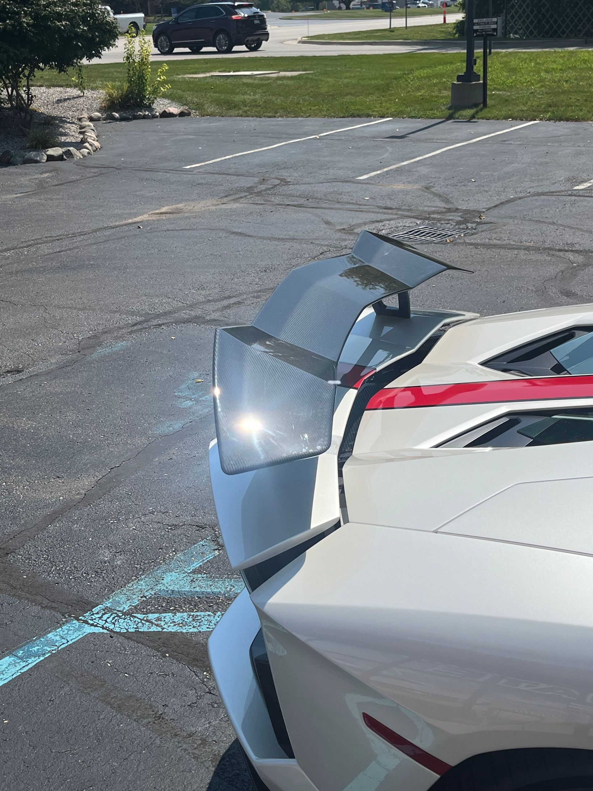 A white sports car with a spoiler is parked in a parking lot.