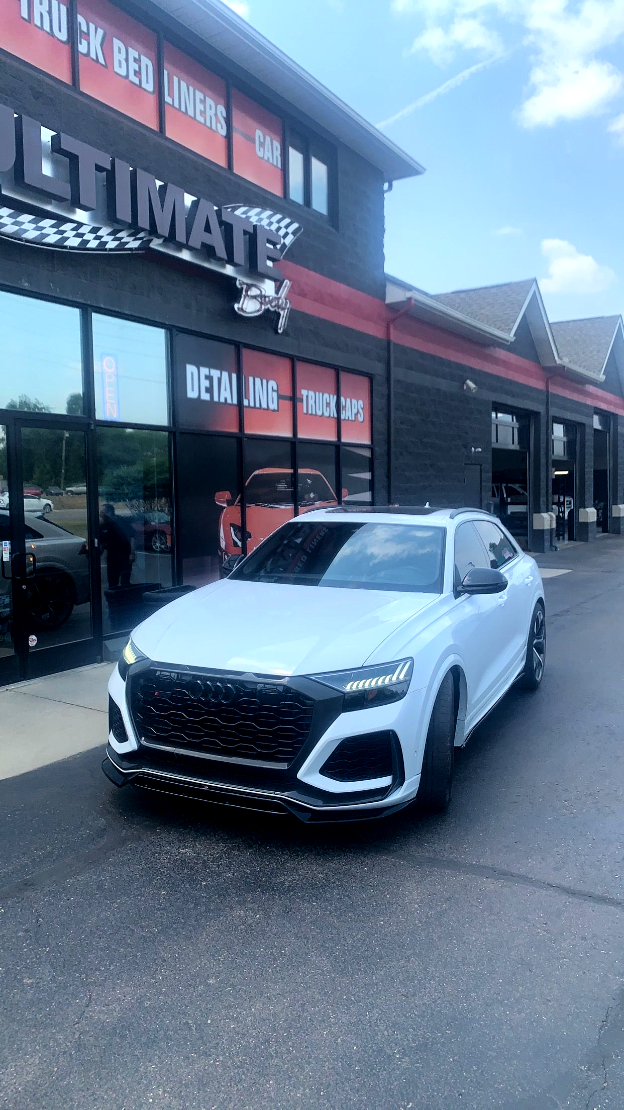 A white car is parked in front of a building.