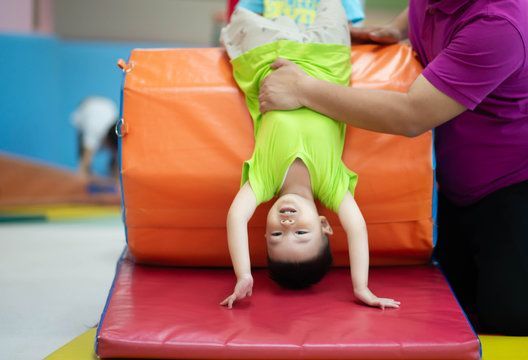 A young boy is doing a handstand on a mat.