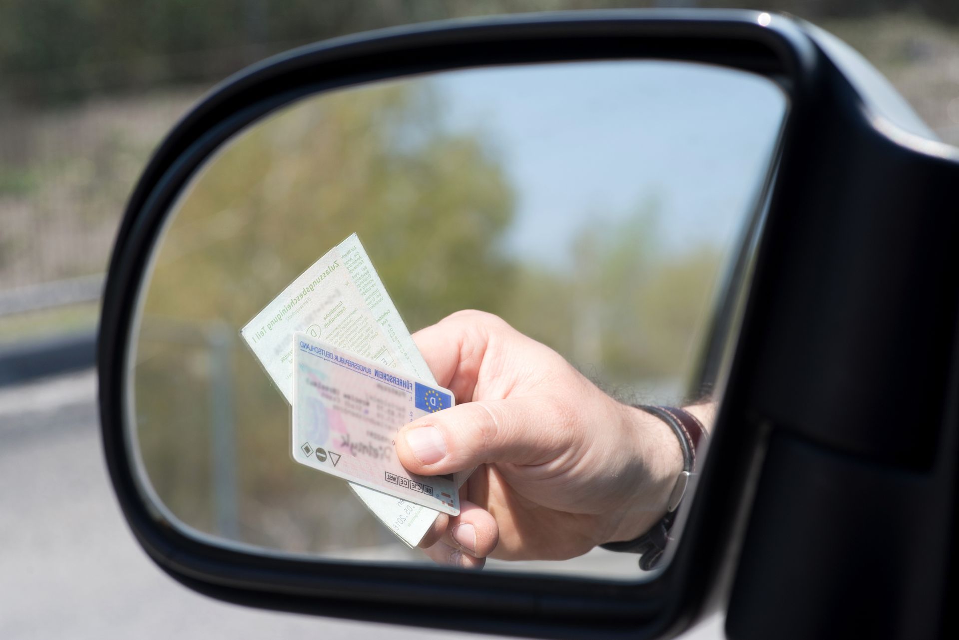 A person holding two cards, presumably a driver's license and registration card.